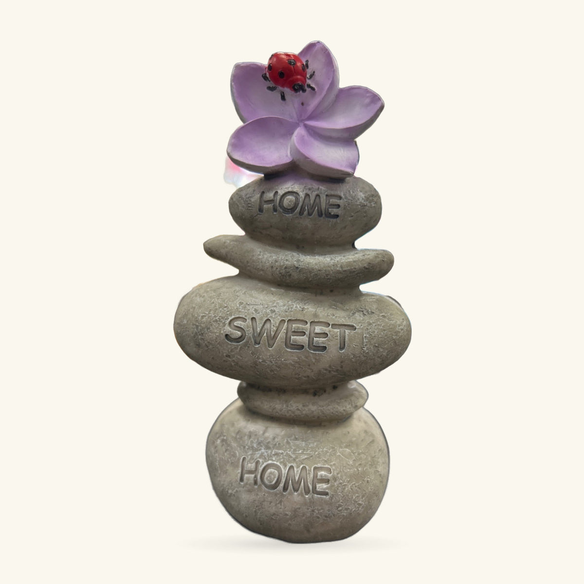 Stacked stone ornament with 'Home Sweet Home' text, topped with purple flower and red ladybug