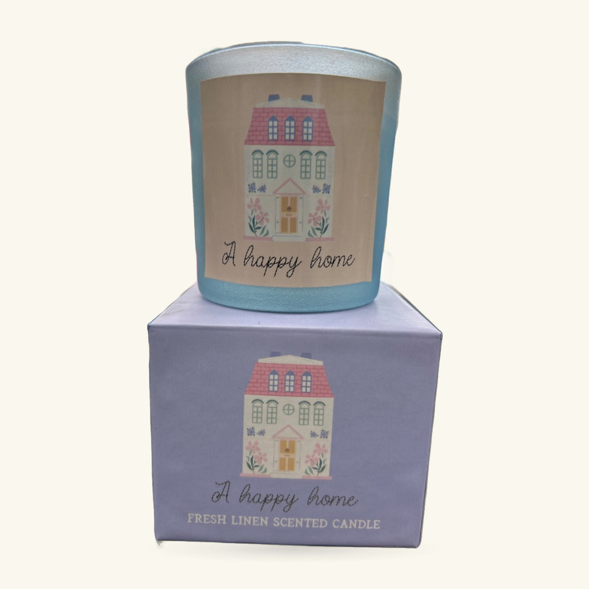 A pale blue cylindrical candle with decorative house illustration and 'A happy home' text, shown with its lavender box