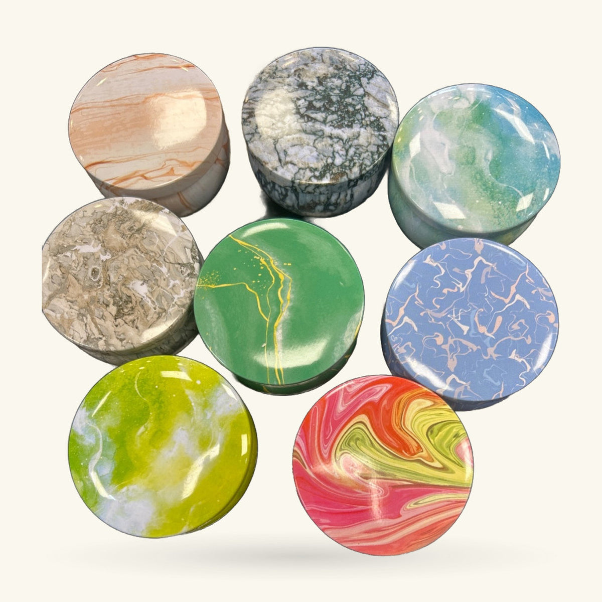 Eight circular tins with tie dye and natural stone finishes in greens, blues, reds, and earth tones