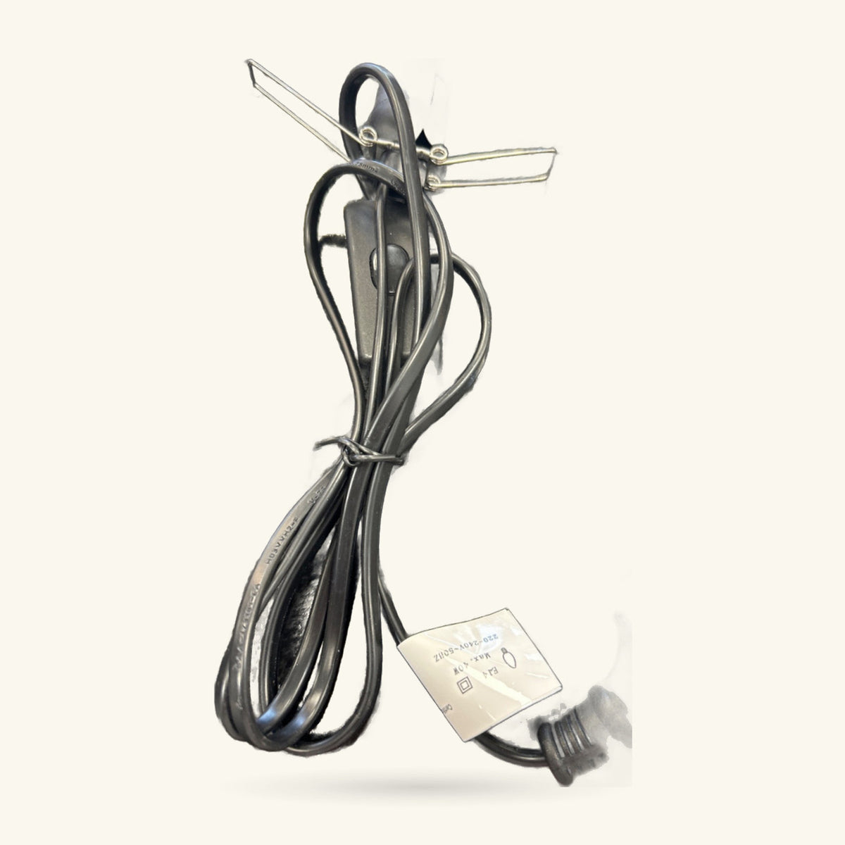 Black coiled power cord with dimmer switch and metal prongs, product label attached