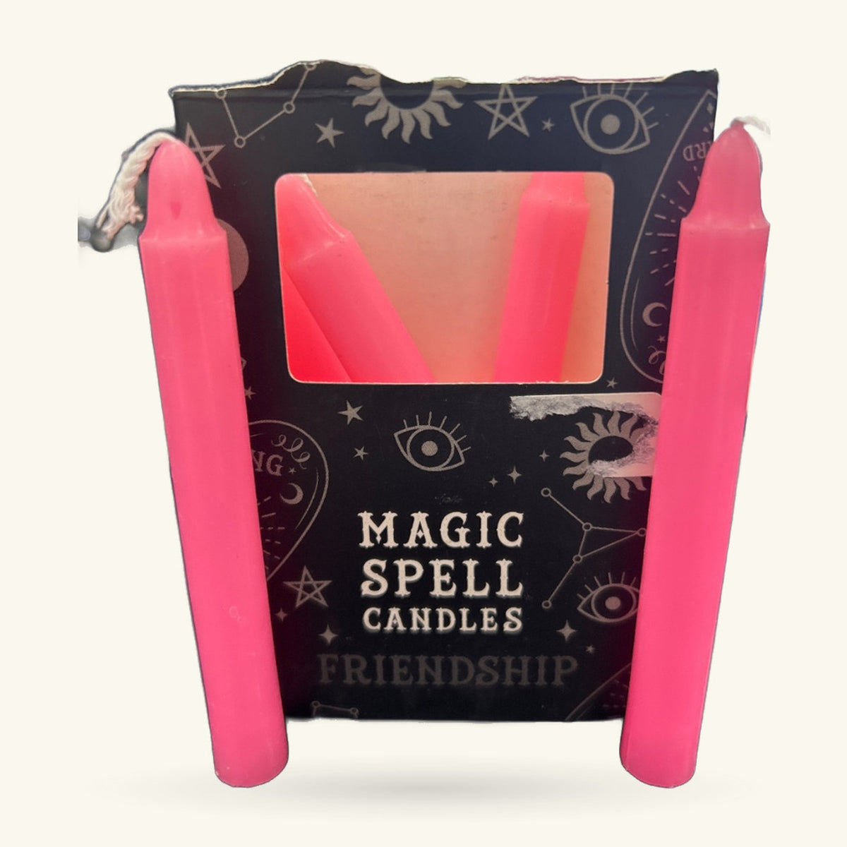 Pink Friendship Spell Candle in bright fuchsia, displayed in dark packaging decorated with mystical symbols.