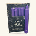 Purple spell candles in a dark box printed with mystical symbols. One single candle displayed in front.