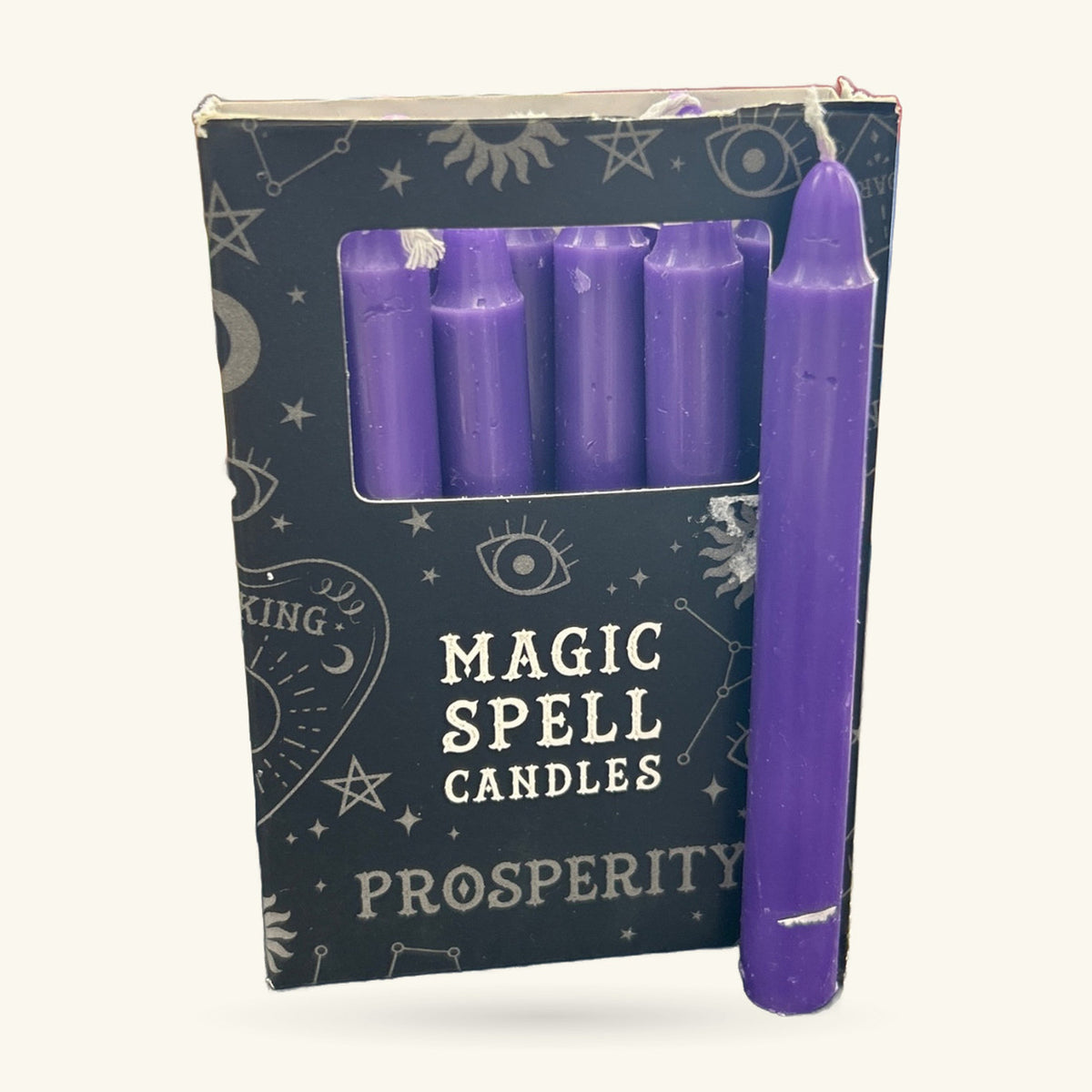 Purple spell candles in a dark box printed with mystical symbols. One single candle displayed in front.