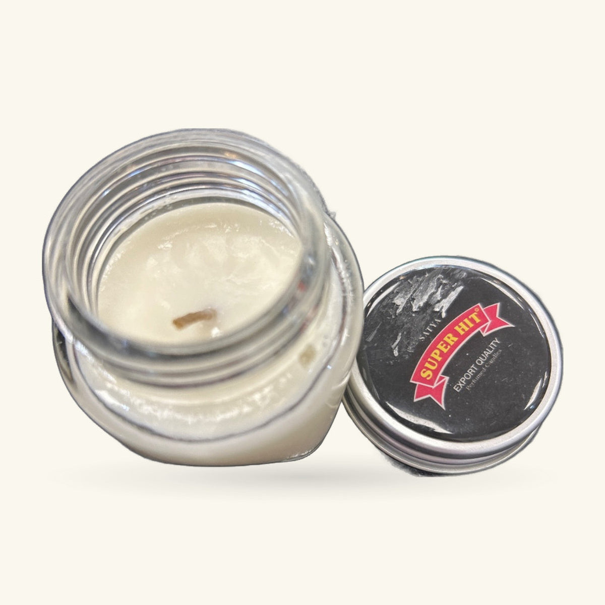 Open jar of Super Hit candle showing pale cream-coloured wax with black lid beside it