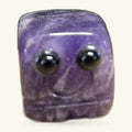 Purple amethyst block carved into a rounded square face with two black eyes and a simple smile
