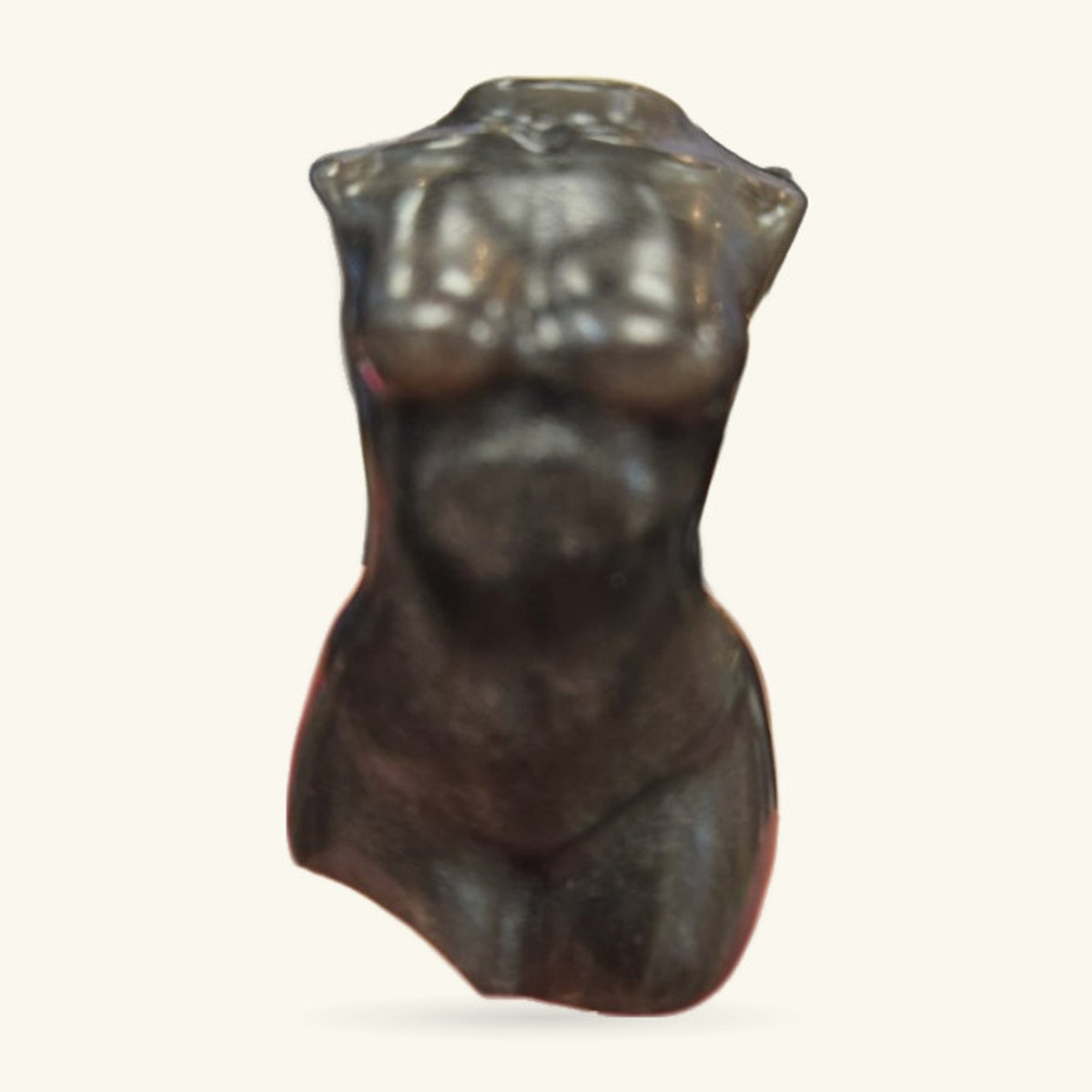 Dark polished obsidian torso carving, headless, with smooth curves and a wavy top edge