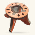 Orange wooden sphere stand with dark inlaid diamond shapes and metal support arms, viewed from above