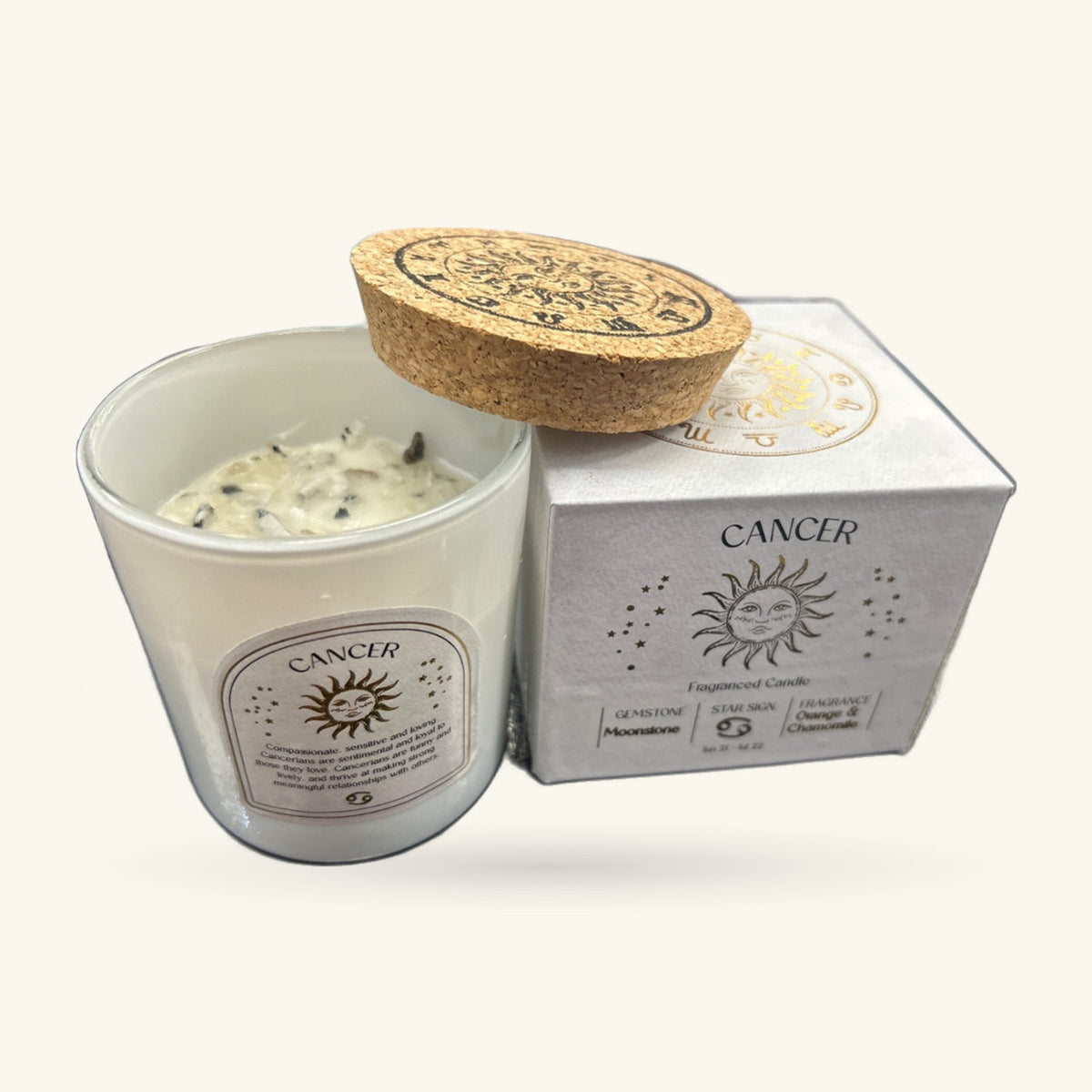 Cancer zodiac candle in clear glass with cream wax, cork lid with embossed design, and grey gift box with sun logo