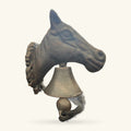 Brass horse head door knocker with decorative mane and bell, mounted on a cone-shaped base.