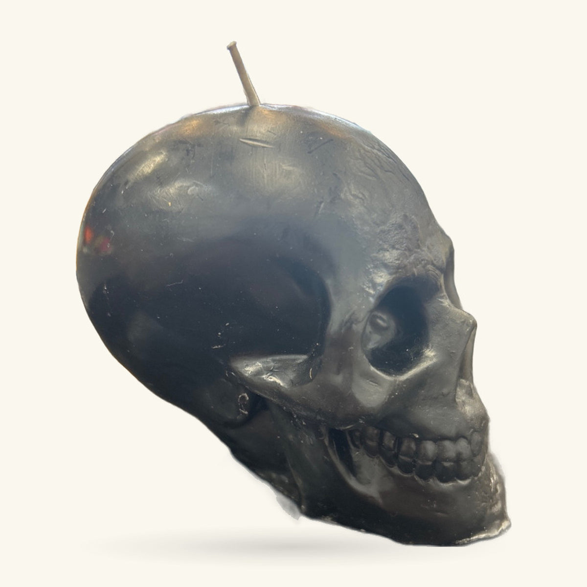 Black skull-shaped candle with a taper wick, shown in profile against a light background