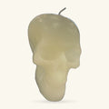 Cream-coloured skull-shaped candle with a grey stem, shown against a light background.