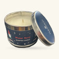 Winter Berry scented soy wax candle in dark blue tin with lid removed, showing cream wax and wooden wick