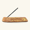 Wooden incense holder with brass moon and stars inlay, black stick inserted at angle