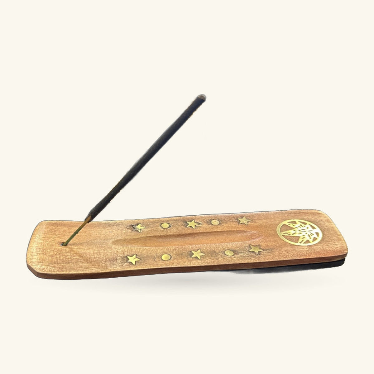 Wooden incense holder with brass leaf and stars, black incense stick resting on top