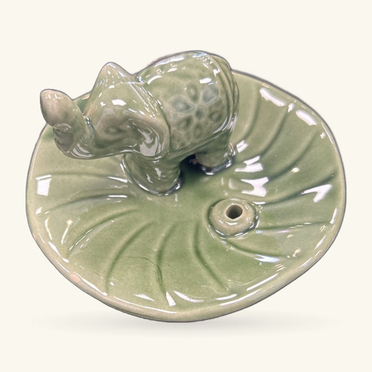 Pale green ceramic round dish with two elephant figures at the rim and a small hole for incense sticks