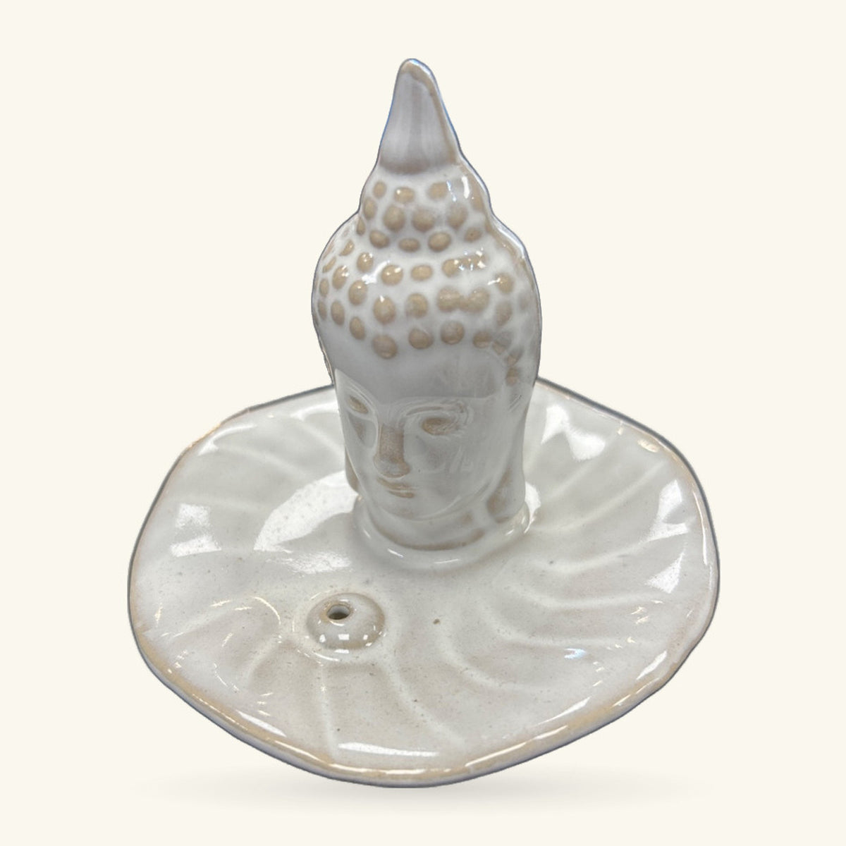 Cream ceramic buddha head incense holder with textured ushnisha, sitting on a round dish base