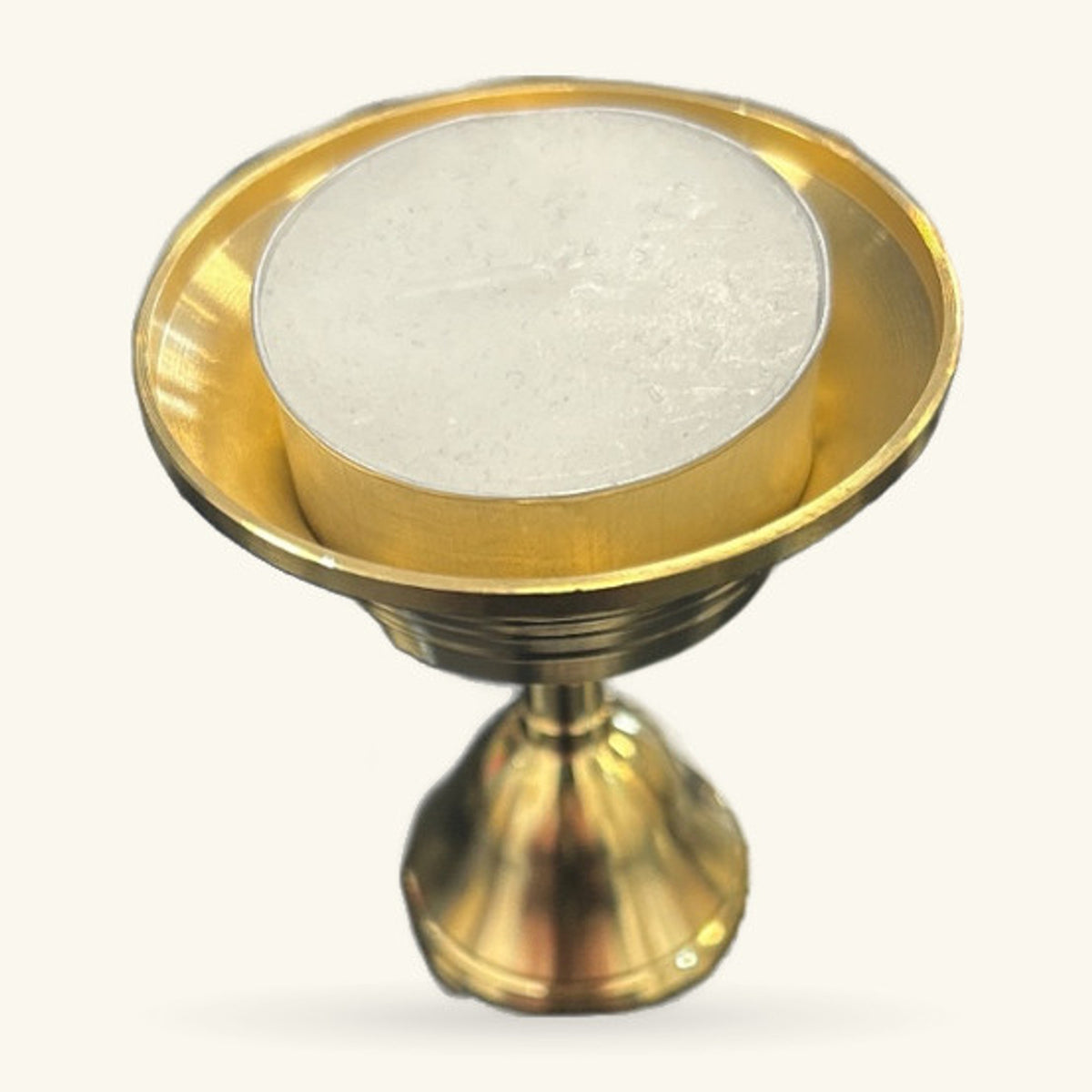 Gold metal tealight holder with white circular inlay, pedestal base, angled view