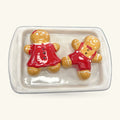 Two ceramic gingerbread figures in red outfits on a white ceramic baking tray, salt and pepper shakers