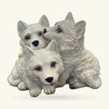 Three white ceramic wolf pup figurines huddled together, with black noses and blue eyes.