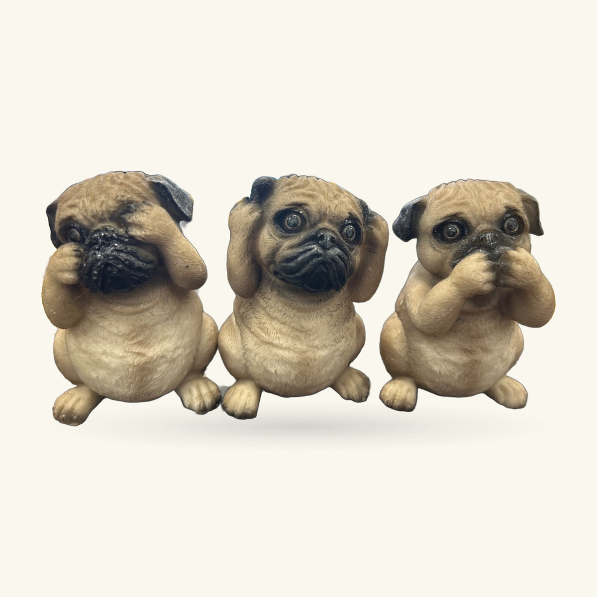Three cream and black pug figurines in sitting poses, each with paw raised to face in different gestures