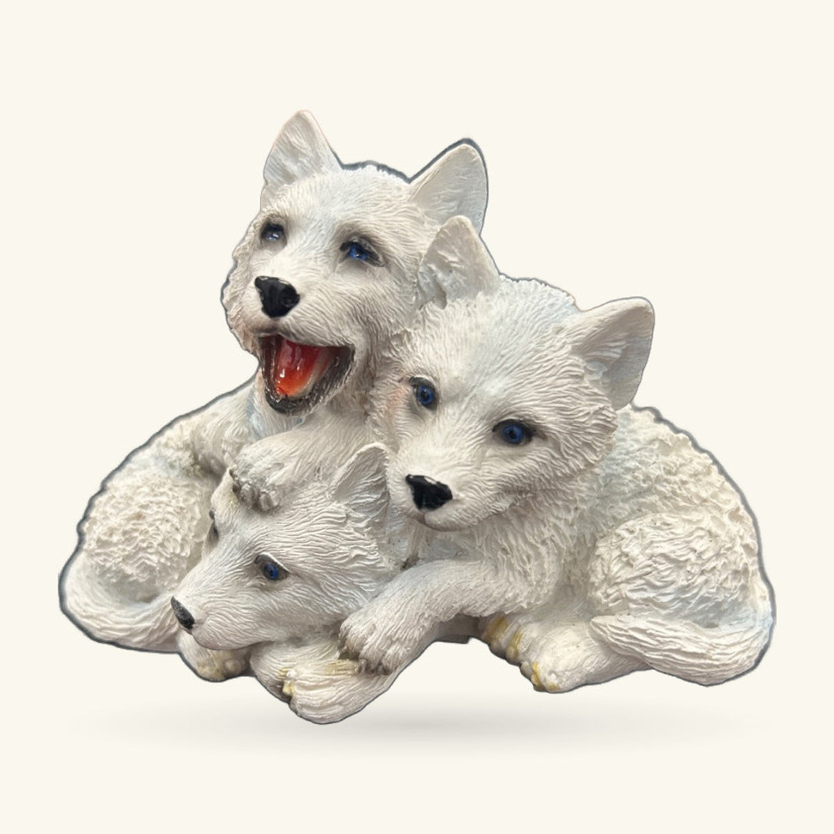 Three white wolf pup figurines huddled together, with one pup's mouth open in a playful expression