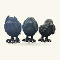 Three dark raven figurines standing side by side, each with detailed feathered wings and talons, against a neutral background.