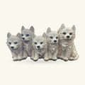 Five white wolf pup ornaments sitting in a row, each with blue eyes and black noses