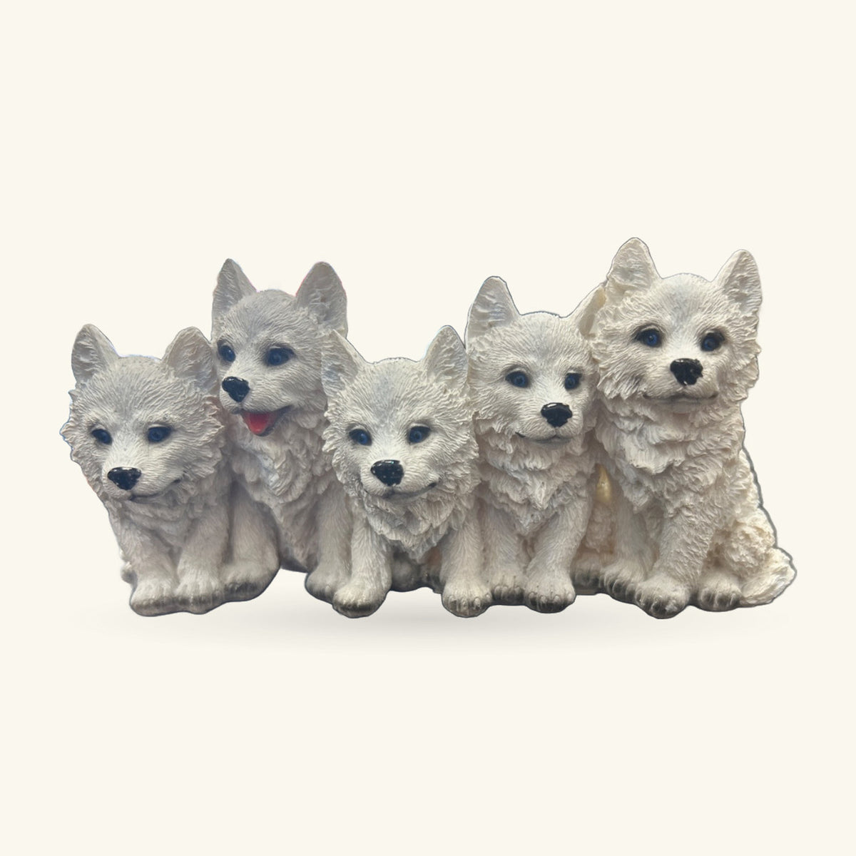 Five white wolf pup ornaments sitting in a row, each with blue eyes and black noses