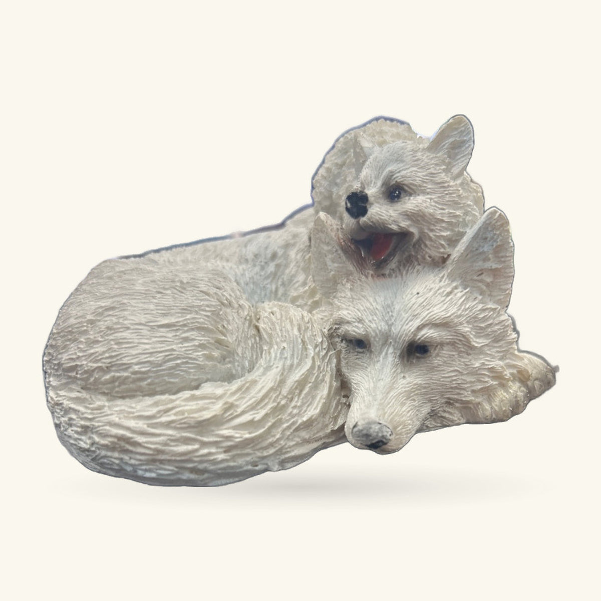 White resin ornament of a wolf pup sitting on a mother wolf's back, both with gentle expressions